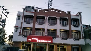 Un hotel de varios pisos con un llamativo letrero rojo que dice "HOTEL Aashirwad".