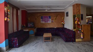 Una habitación con sofá modular, una pequeña mesa de madera y una pared decorativa con un póster.