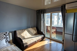 Relax in this cozy living space with a sofa and sliding glass door leading to an outdoor area.