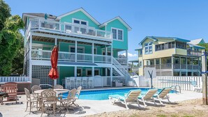 A two-story building with a pool, outdoor seating, and a staircase leading to the upper floor. - Family Tradition - Duck Landing, Oceanside, 130 Yds to Beach, Pool, Hot Tub, Tiki Bar (Duck)