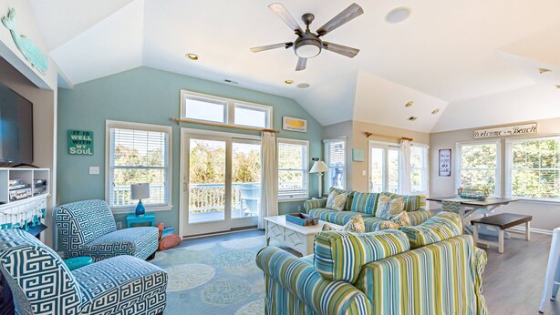 A spacious living room with a large sofa set, a television, and a ceiling fan. - Family Tradition - Duck Landing, Oceanside, 130 Yds to Beach, Pool, Hot Tub, Tiki Bar (Duck)