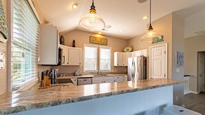 A kitchen with white cabinets, a granite countertop, and pendant lighting. - Family Tradition - Duck Landing, Oceanside, 130 Yds to Beach, Pool, Hot Tub, Tiki Bar (Duck)