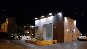 Un edificio moderno con techo plano, una entrada pequeña y un camino de entrada pavimentado.