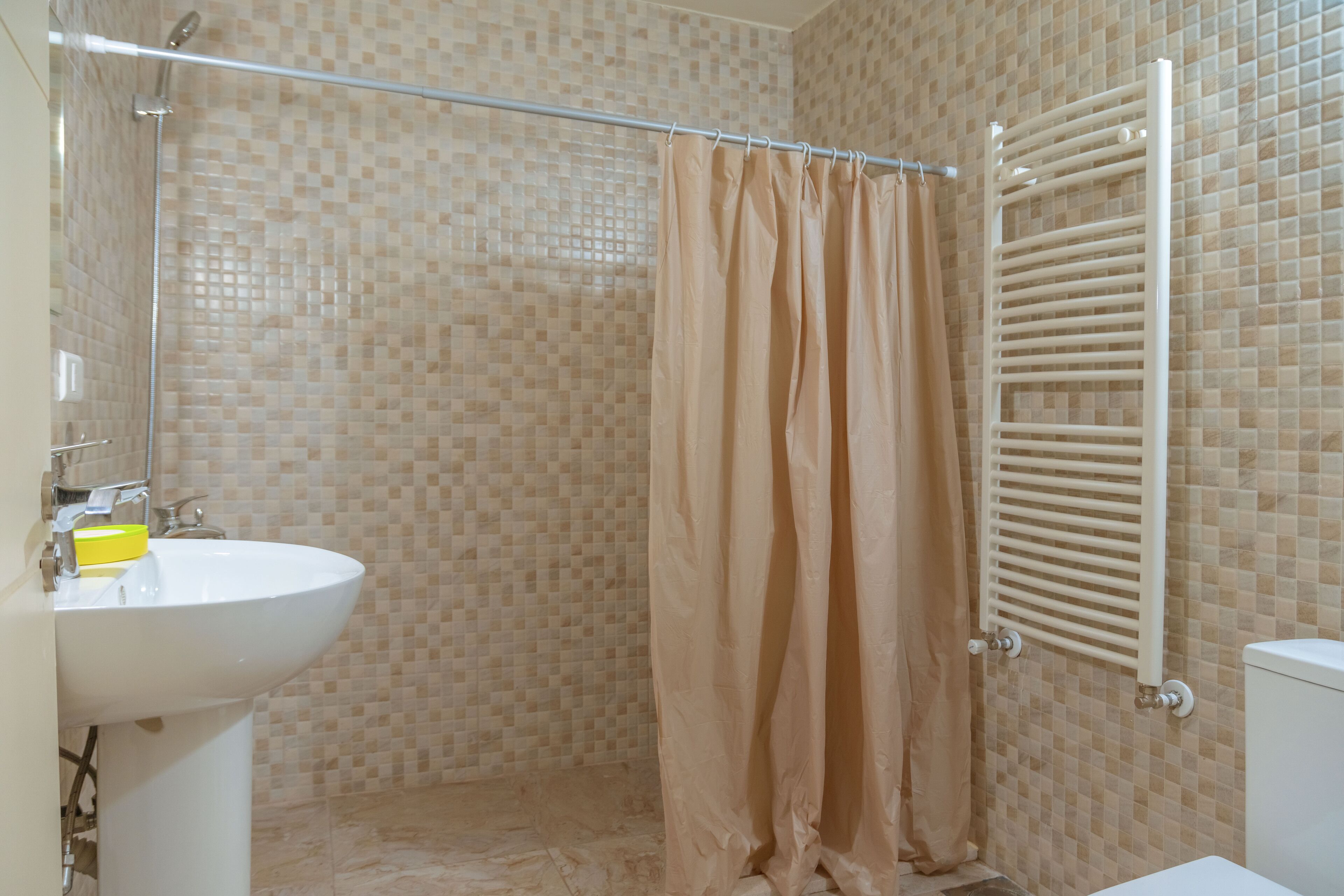 A bathroom with a shower, a sink, and a towel rack.