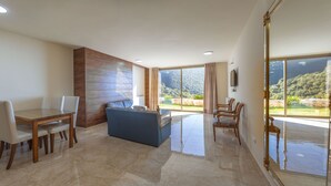 Amplia sala de estar con comedor, sofá y vistas a un paisaje montañoso a través de grandes ventanales.