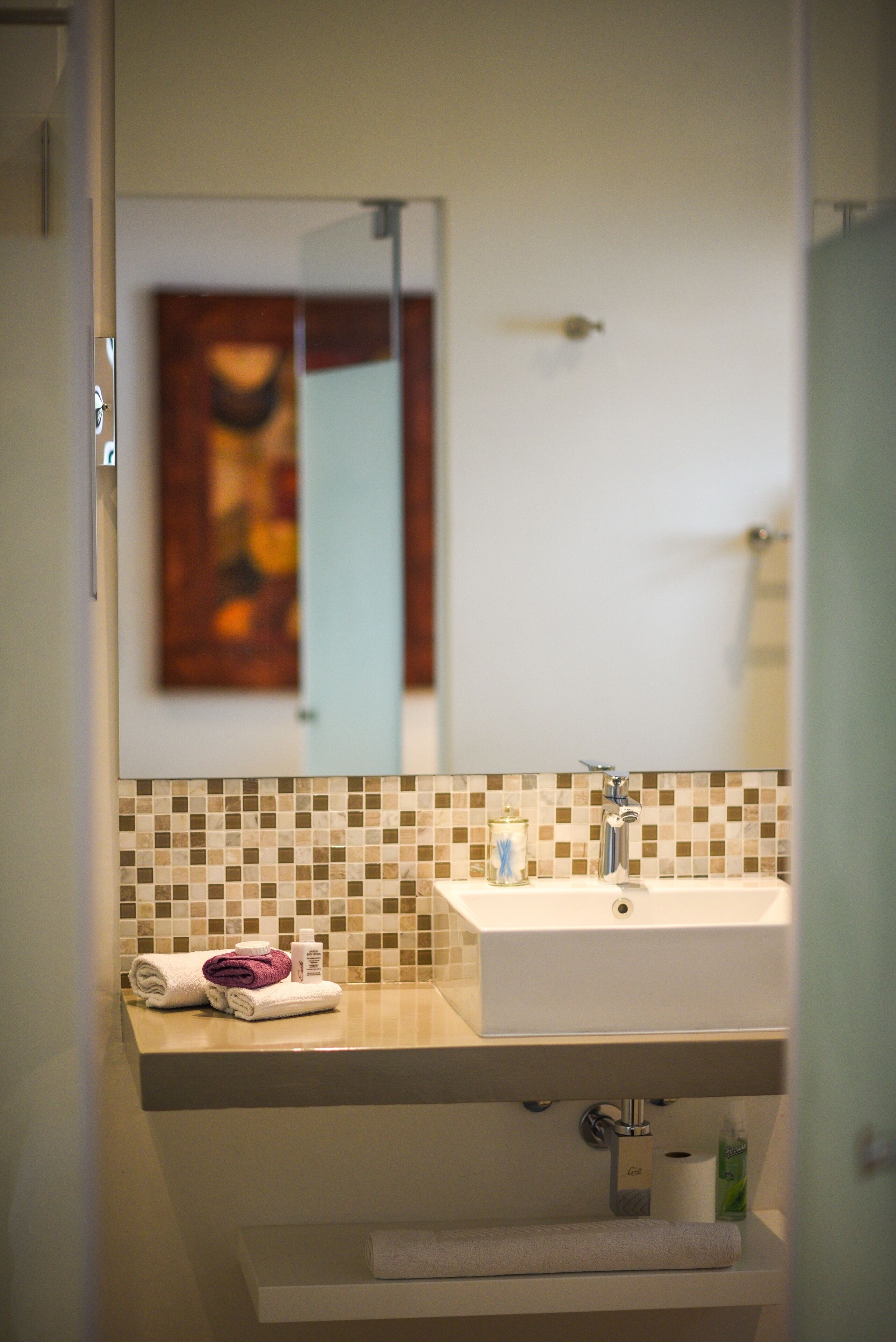 A bathroom with a white sink, a mirror, and a tiled backsplash.
