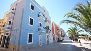 A multi-story building with balconies, a clear sky, and palm trees. - Le Nereidi B&B (Margherita di Savoia)