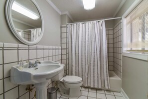 A bathroom with a white sink, toilet, and shower curtain. - Pinners Cove: Hot Tub, Fire Pit, Prime Location (Asheville)