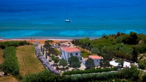 Ein Küstenanwesen mit einem weißen Gebäude, einem Garten mit verschiedenen Pflanzen und Blick auf das Meer.