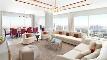 A spacious living room with a large sofa, a coffee table, and a dining area with red chairs and a white table.