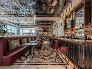 Un área de bar moderna con asientos, una barra y techo de cristal.