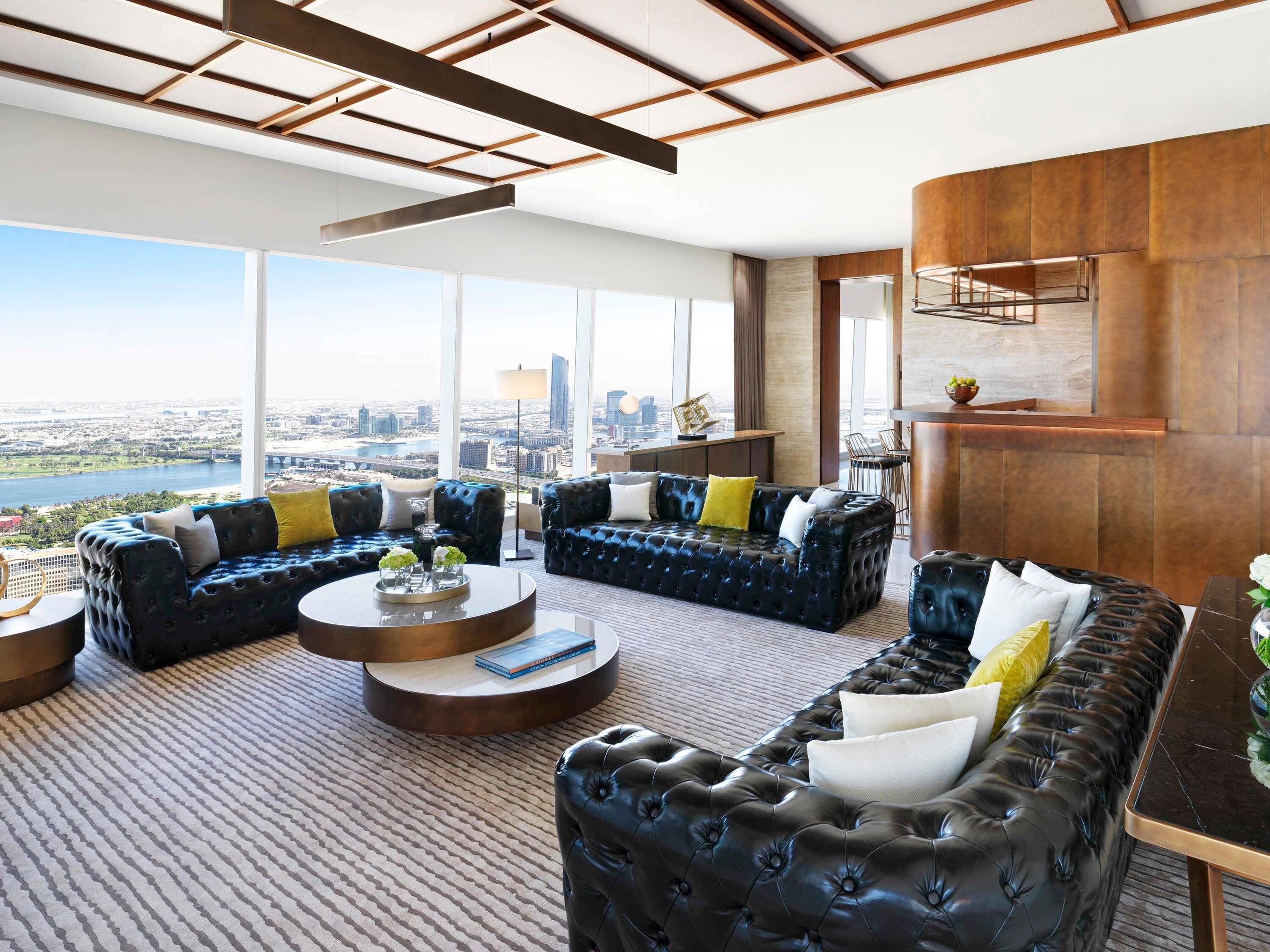 A spacious living area with leather sofas, a coffee table, and a view of a cityscape.