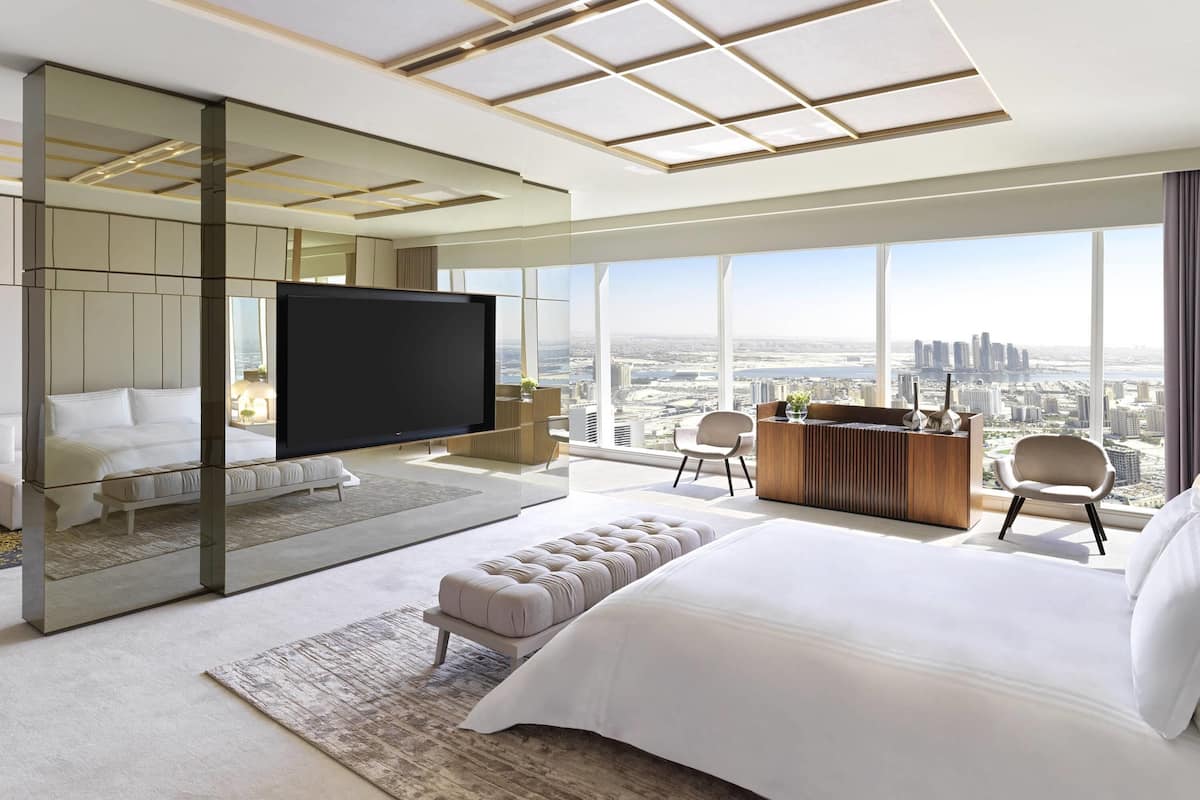Una habitación de hotel moderna con una cama grande, televisión, escritorio y vistas a la ciudad.
