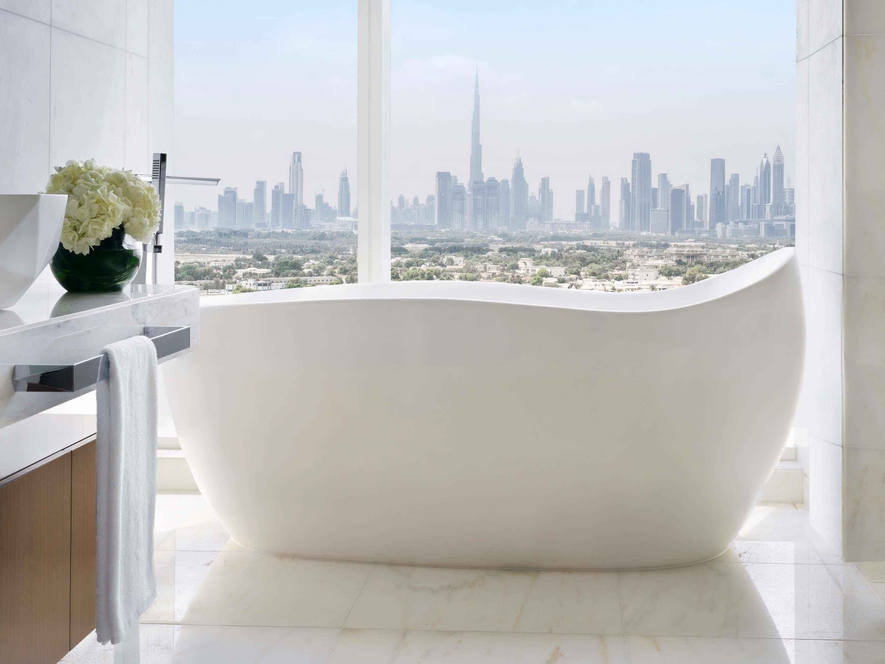 Une salle de bain moderne avec une baignoire sur pieds, un comptoir en marbre et une grande fenêtre offrant une vue sur le paysage urbain.