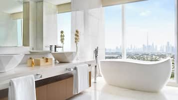 Een moderne badkamer met een vrijstaand bad, een grote spiegel en uitzicht op een stadshemelbeeld.