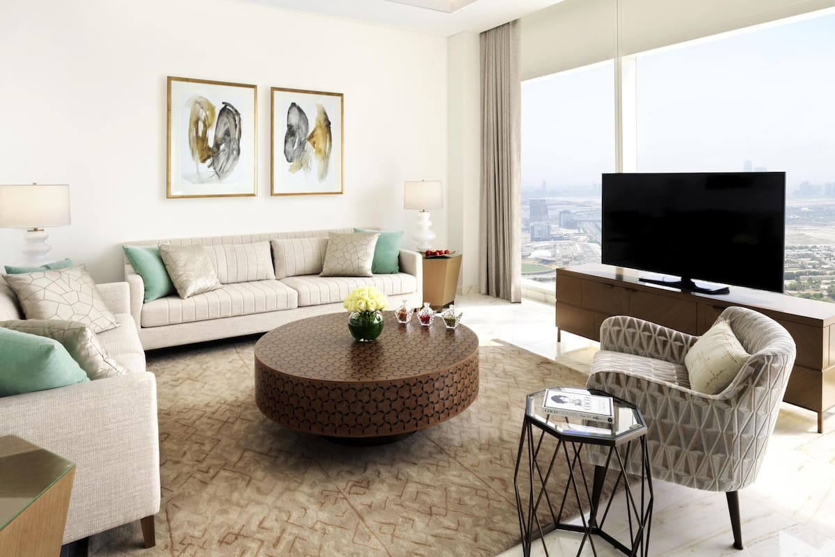 A modern living room with a sofa, coffee table, and armchair, a flat-screen TV, and artwork on the wall.