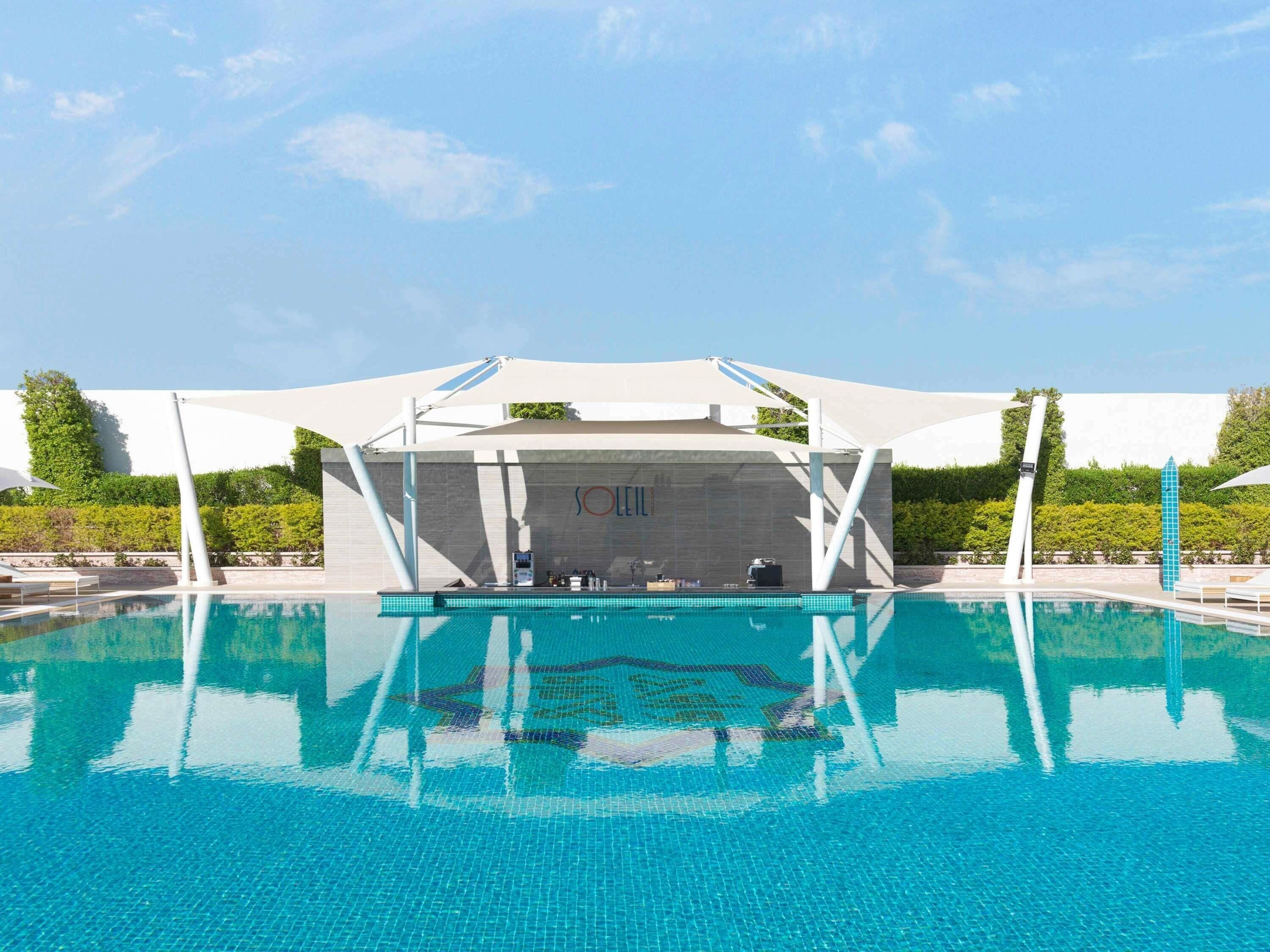 Una piscina al aire libre, camas de piscina con cargo, sombrillas