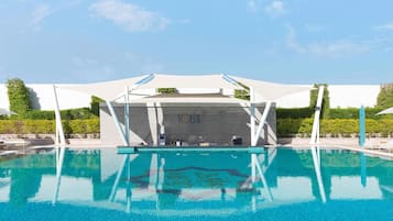 Una piscina al aire libre, camas de piscina con cargo, sombrillas