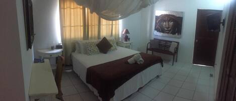 A bedroom with a bed, bedside table, lamp, and a painting on the wall.