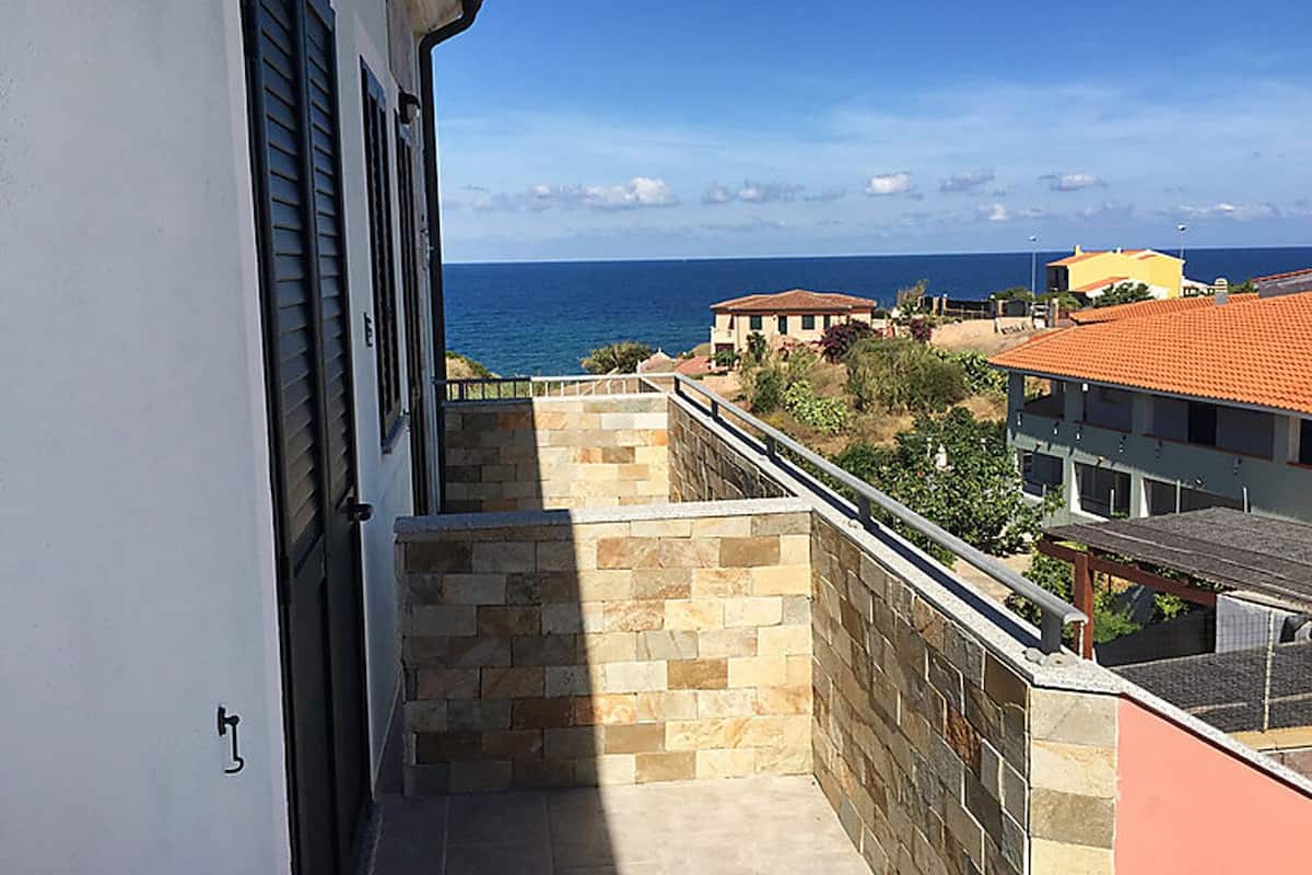 Un balcon avec un mur en pierre et une vue sur la mer.