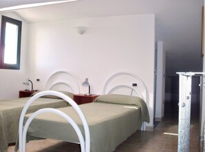 A room with two beds, each with a white headboard and a bedside table with a lamp. - Le Terrazze sul Mare (Valledoria)