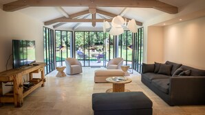 A spacious living room with a large window, a sofa, a coffee table, and a TV. - Domaine du Buc  Les Gites de Prestige (Marssac-sur-Tarn)