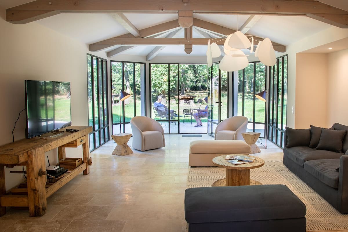 A spacious living room with a large window, a sofa, a coffee table, and a TV.
