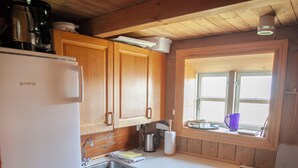 A compact kitchen with wooden cabinets, a white refrigerator, a sink, and a stove. - The Real Faroese Experience (Skalavik)