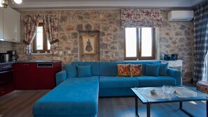 Un salon avec un canapé bleu, une table basse et un coin cuisine doté de meubles rouges.