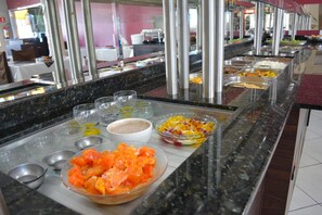 A buffet setup with various food items and condiments. - Hotel São Francisco by RB Hotelaria (Ubirata)