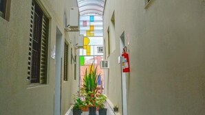 Un pasillo con techo de cristal, plantas en macetas y un extintor.