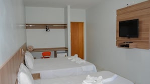 Habitación de hotel con dos camas, un televisor montado en la pared y un escritorio de madera con una silla.