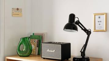 A wooden desk with a black desk lamp, a green vase, and a framed picture on the wall.