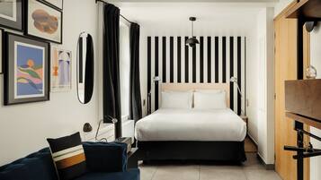 Een moderne slaapkamer met een groot bed, een nachtkastje, een bureau, een stoel en een kledingkast.