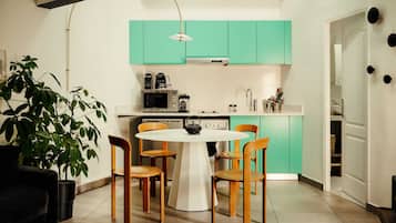 Una cocina moderna con armarios color turquesa, una mesa de comedor blanca y sillas de madera.