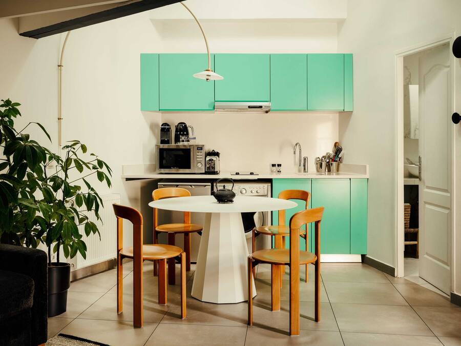 Una cocina moderna con armarios color turquesa, una mesa de comedor blanca y sillas de madera.