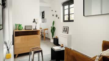 A modern living room with a wooden cabinet, a small table, a brown sofa, and a potted plant.
