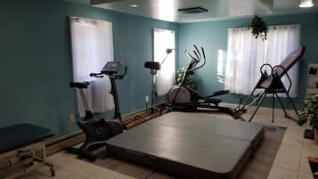 Een fitnessruimte met trainingsapparatuur, een massagetafel en een bank.