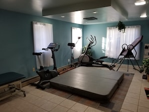 Een fitnessruimte met trainingsapparatuur, een massagetafel en een bank.