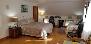 Een slaapkamer met een groot bed, een houten dressoir, een stoel en een bureau met een lamp.