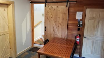 Een houten interieur met een tafel, stoelen, een brandblusser en een telefoon voor noodgevallen.
