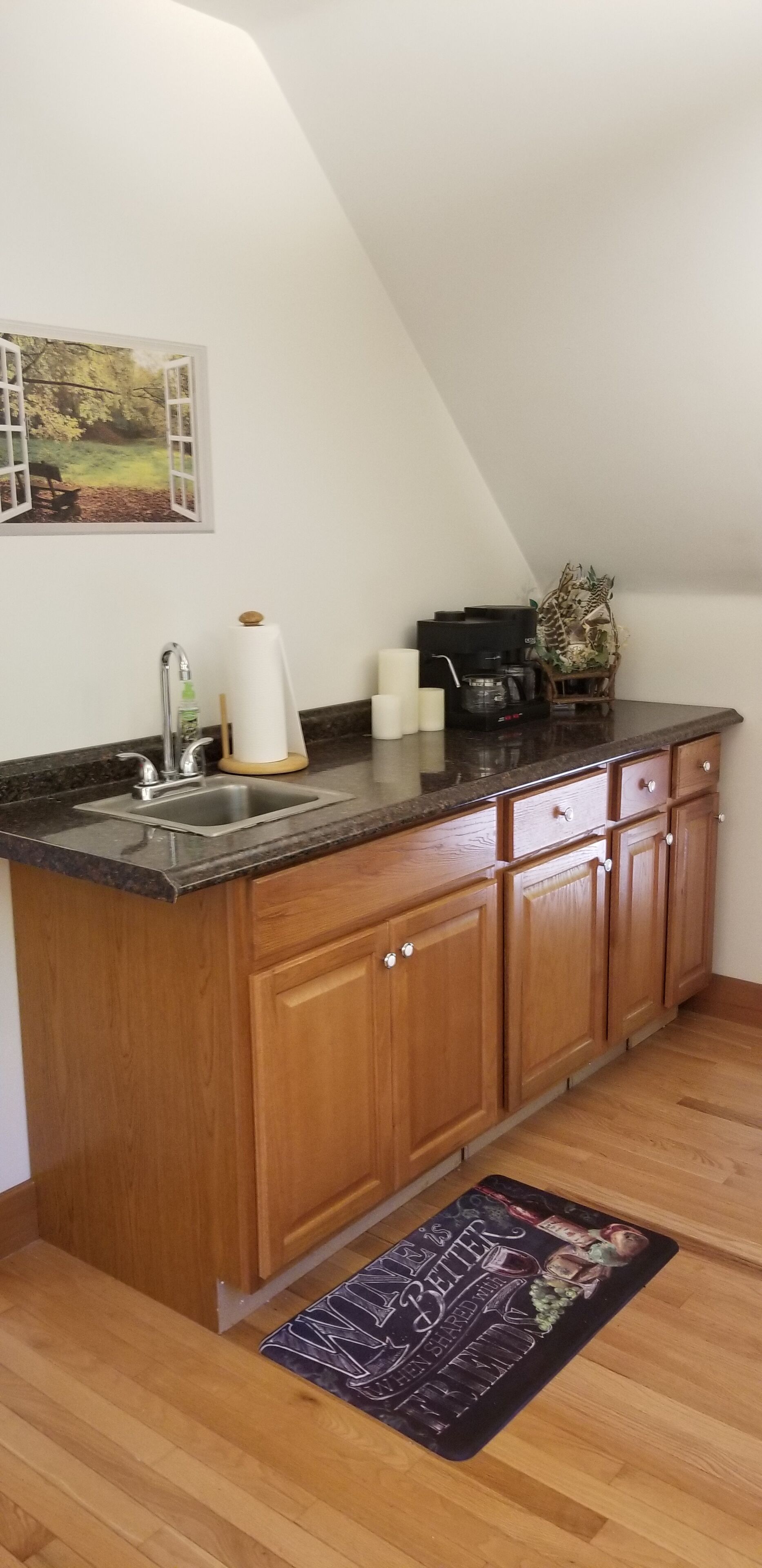 A kitchen with wooden cabinets, a granite countertop, a stainless steel sink, and a small island.