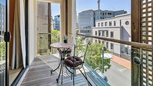 A balcony with a wooden ceiling, a table with chairs, and a view of a cityscape including a tower. - Waterfront Beauty with Parking by Zodiak Stays (Auckland)