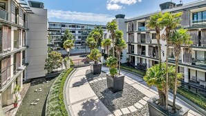 A modern building with balconies, potted plants, and a clear sky. - Waterfront Beauty with Parking by Zodiak Stays (Auckland)