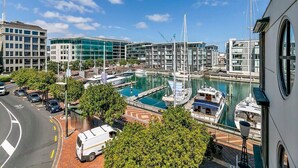 A marina with boats, a road with cars, and modern buildings in the background. - Waterfront Beauty with Parking by Zodiak Stays (Auckland)