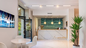 A hotel reception area with a marble floor, a reception desk, and a large painting of dancers. - Tirreno Beachfront Apartments (Massa)