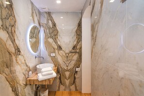 A bathroom with a marble wall, a sink with a mirror, and a shower area. - Tirreno Beachfront Apartments (Massa)