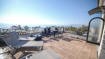 Una terrazza con lettini, tavoli e sedie, con vista sulla costa.