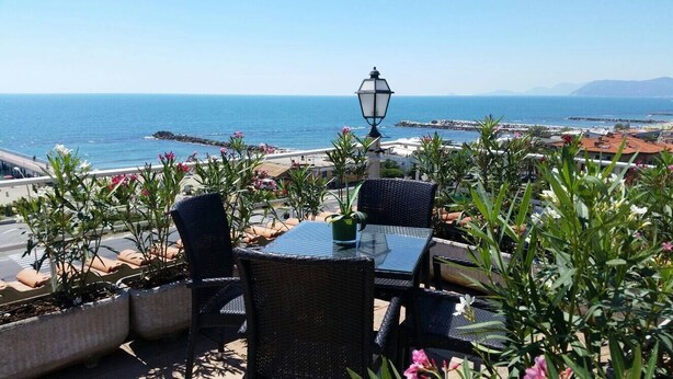 A terrace with outdoor seating, a table, and a street lamp. - Tirreno Beachfront Apartments (Massa)