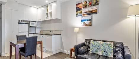 Una sala de estar moderna con una mesa de centro de vidrio, un sofá de cuero y un comedor con una mesa y sillas de madera.